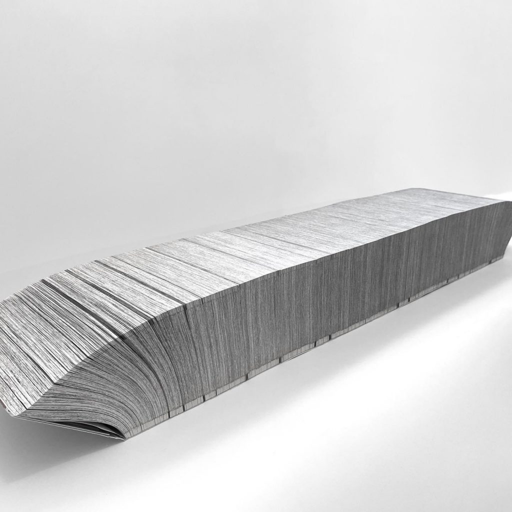 "ONEPIECE" by Ilan Manouach out of its box and placed on its spine, showing how the pages open up.