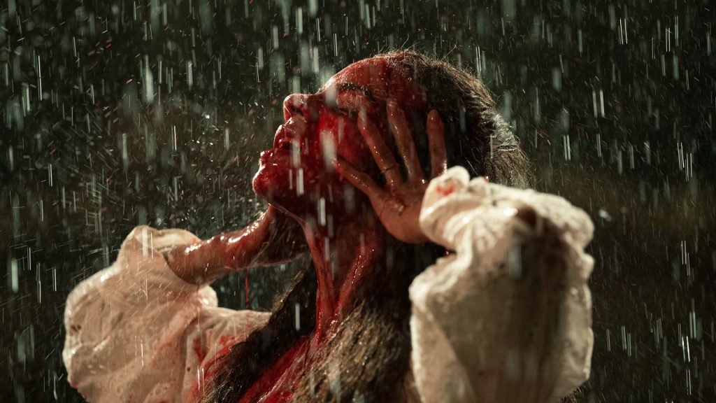 Woman standing in rain with blood on her face