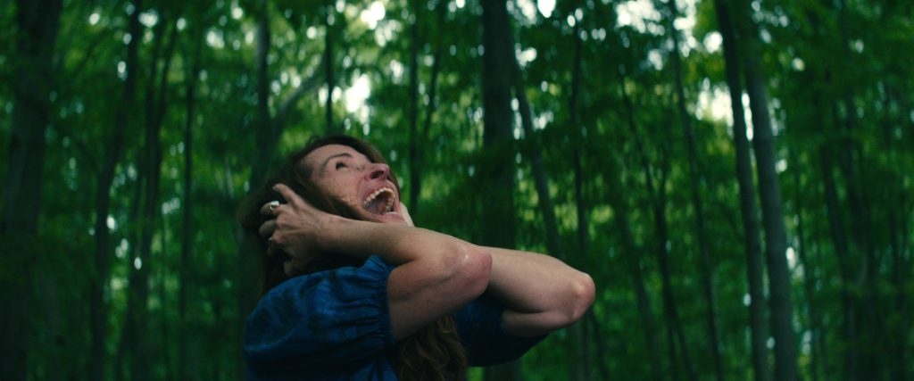 LEAVE THE WORLD BEHIND (2023) Julia Roberts as Amanda, screaming in the woods with her hands over her ears.  CR: Courtesy NETFLIX
