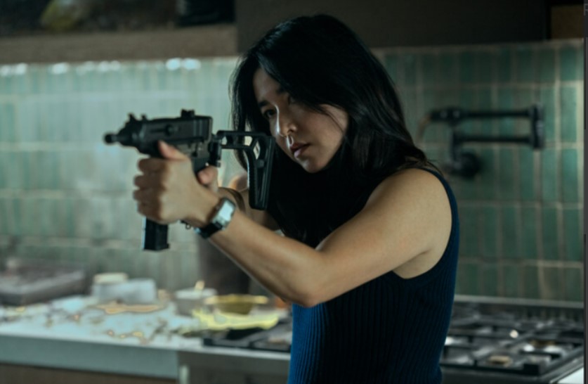 Maya Erskine as Jane Smith in 'Mr. & Mrs. Smith,' pointing a gun in a kitchen