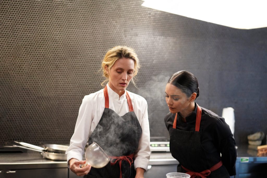 Ruby (Vanessa Hudgens) assesses food made by Sophie (Evelyne Brochu) in 'French Girl'